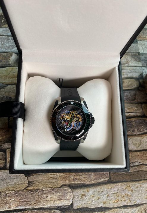 Steel case, black dial with silver feline head motif, black rubber strap ETA quartz movement Water resistance: 20 ATM (660 feet/200 metres) Wrist size adjustable from 161mm to 203mm YA136320 Swiss Made and two year international warranty